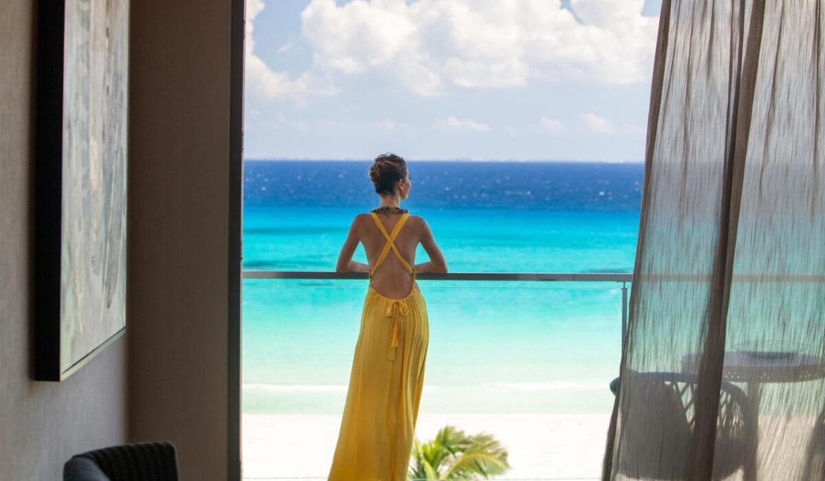 Mulher de costas, com vestido amarelo olhando para o mar